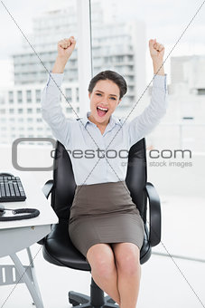Elegant and happy businesswoman clenching fists in office