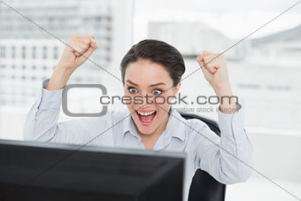Excited businesswoman looks at the computer screen in office