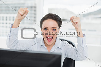 Portrait of an excited businesswoman clenching fists in office