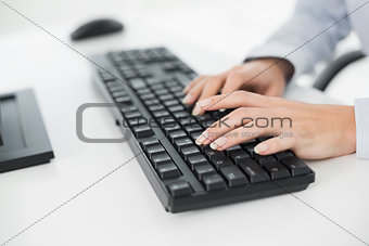 Hands typing on a keyboard in an office