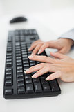 Hands typing on a keyboard in an office