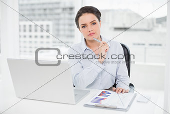 Elegant  businesswoman with graphs and laptop in office