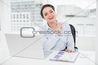Happy businesswoman with graphs and laptop in office