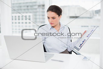 Businesswoman with graphs and laptop in office