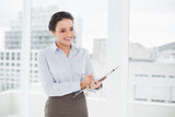 Smiling elegant businesswoman with clipboard in office