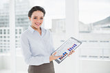 Smiling elegant businesswoman pointing at graphs in office