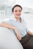 Smiling well dressed young woman sitting on sofa