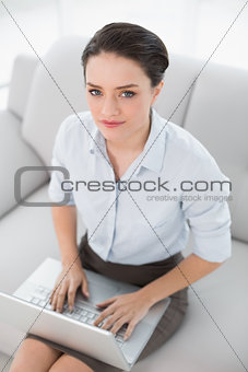 Well dressed young woman using laptop on sofa