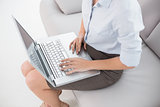 Well dressed young woman using laptop on sofa