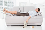 Woman with laptop sleeping on sofa at home