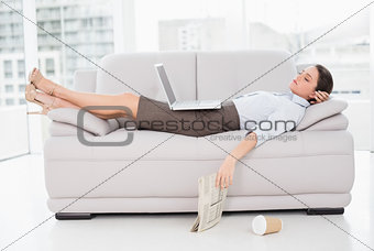 Woman with laptop sleeping on sofa at home