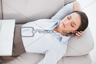 Woman with laptop lying on sofa