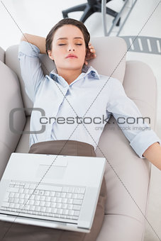 Woman with laptop lying on sofa at home