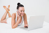 Smiling casual woman using cellphone and laptop