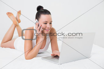 Smiling casual woman using cellphone and laptop