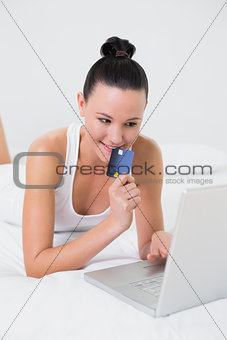Casual woman doing online shopping in bed