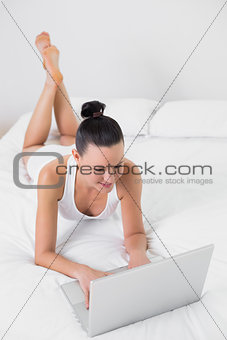 Casual woman using laptop in bed