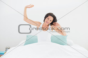 Wmiling woman stretching her arms in bed