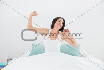 Young woman stretching arms in bed