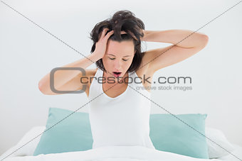 Sleepy woman yawning while stretching her arms in bed