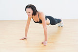 Determined sporty woman doing push ups in fitness studio