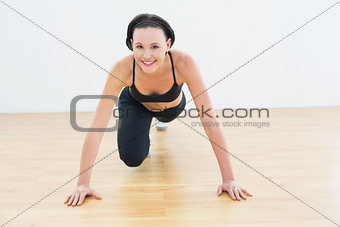 Smiling sporty woman doing push ups in fitness studio
