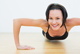 Smiling woman doing push ups in fitness studio