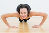 Smiling beautiful woman doing push ups in fitness studio