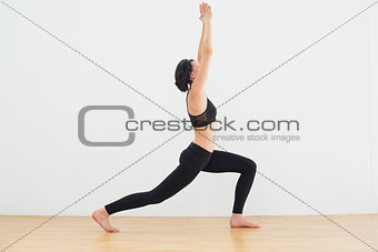Sporty woman doing the warrior pose in fitness studio