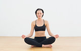 Toned woman sitting in lotus pose with eyes closed