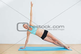 Portrait of a slim woman doing the side plank yoga pose