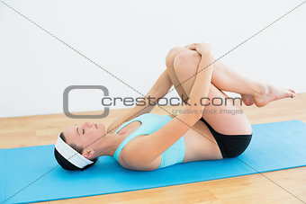 Woman in supine wind release posture on yoga mat