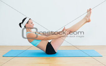 Fit woman doing the boat pose on yoga mat