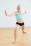 Smiling woman doing the warrior yoga pose in fitness studio