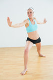 Toned woman doing the warrior yoga pose in fitness studio