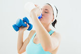 Toned woman with dumbbells drinking water