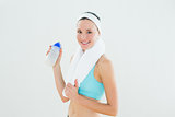 Smiling woman with towel around neck holding water bottle