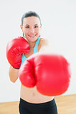Beautiful woman in red boxing gloves at fitness studio