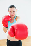 Beautiful woman in red boxing gloves at fitness studio