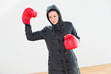 Tought woman in hooded jacket and red boxing gloves