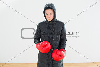 Tough woman in hooded jacket and red boxing gloves
