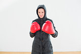 Tough woman in hooded jacket and red boxing gloves