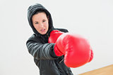Determined young female boxer in red boxing gloves