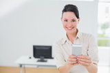 Smiling businesswoman holding a cellphone in office