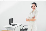 Businesswoman wearing headset with arms crossed in office