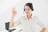 Businesswoman wearing headset while gesturing ok sign in office