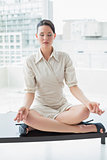 Elegant businesswoman in lotus position with eyes closed at office