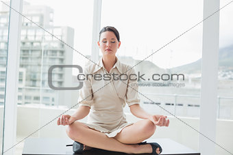 Businesswoman sitting in lotus position with eyes closed at office