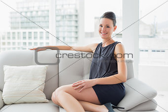 Smiling well dressed woman sitting on sofa at home