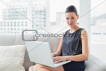 Beautiful well dressed young woman using laptop on sofa